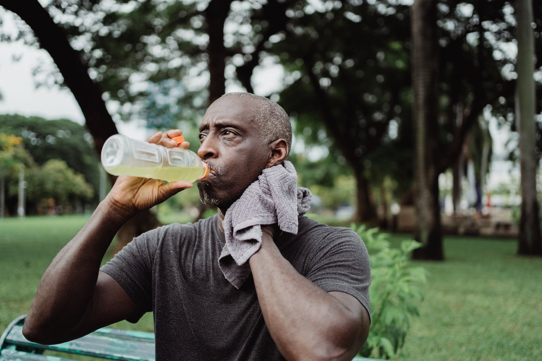 man in black crew neck t shirt drinking yellow liquid from plastic bottle
